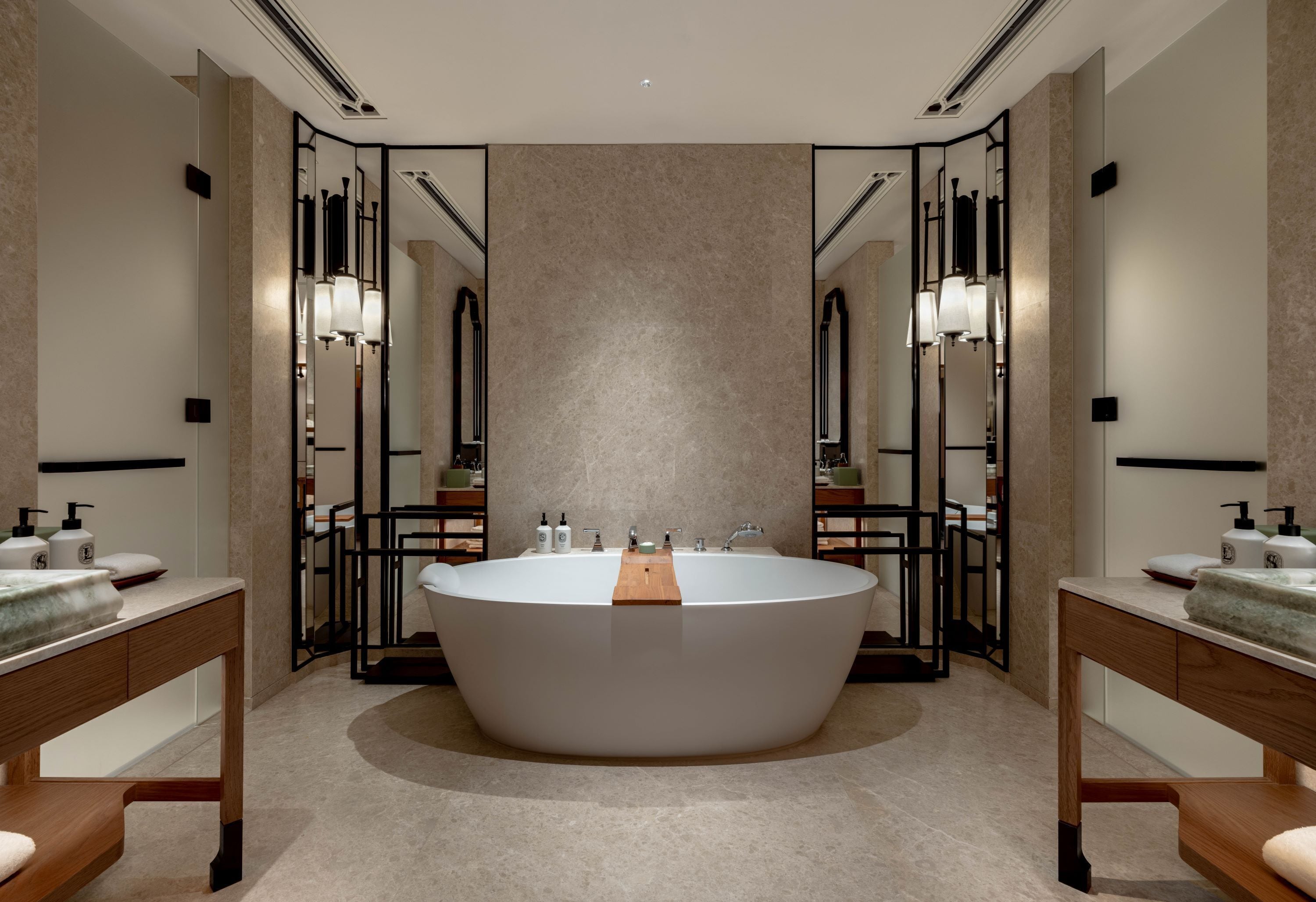 Ein modernes Badezimmer mit freistehender Badewanne, zwei Waschbecken und großen Spiegeln.
