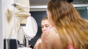 Une salle de bain équipée d’un miroir, d’un lavabo et d’un sèche-cheveux.
