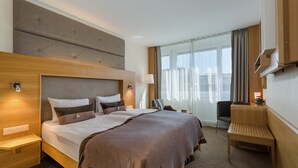 Una habitación de hotel con una cama grande, mesitas de noche, un escritorio y una silla.