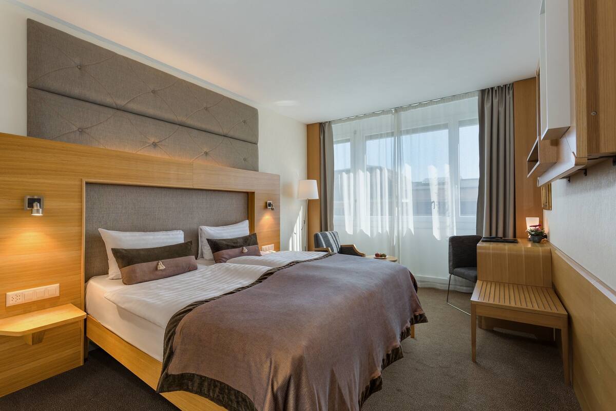 Hotellihuone, jossa on suuri sänky, yöpöydät, työpöytä ja tuoli.