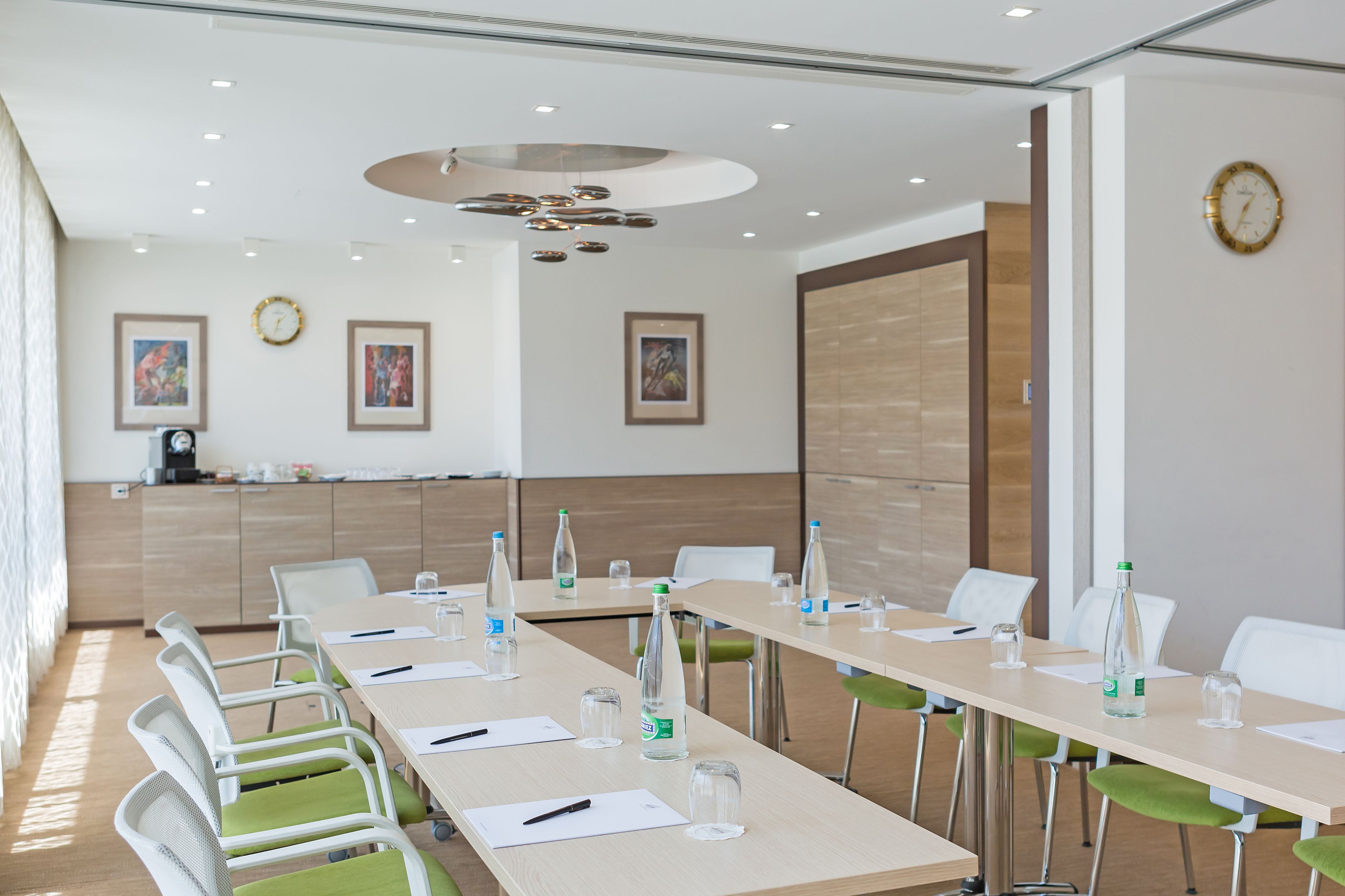 Una sala conferenze con lunghe tavolate, sedie e bottiglie d'acqua.