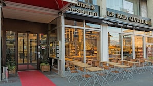 Un restaurante con terraza y una entrada con alfombra roja.