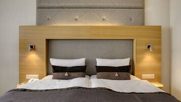 A modern hotel room with a tufted headboard, two bedside tables, and a neutral color scheme.
