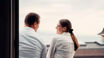 Un couple se tient près d’une fenêtre, d’où l’on peut admirer la vue sur la ville.