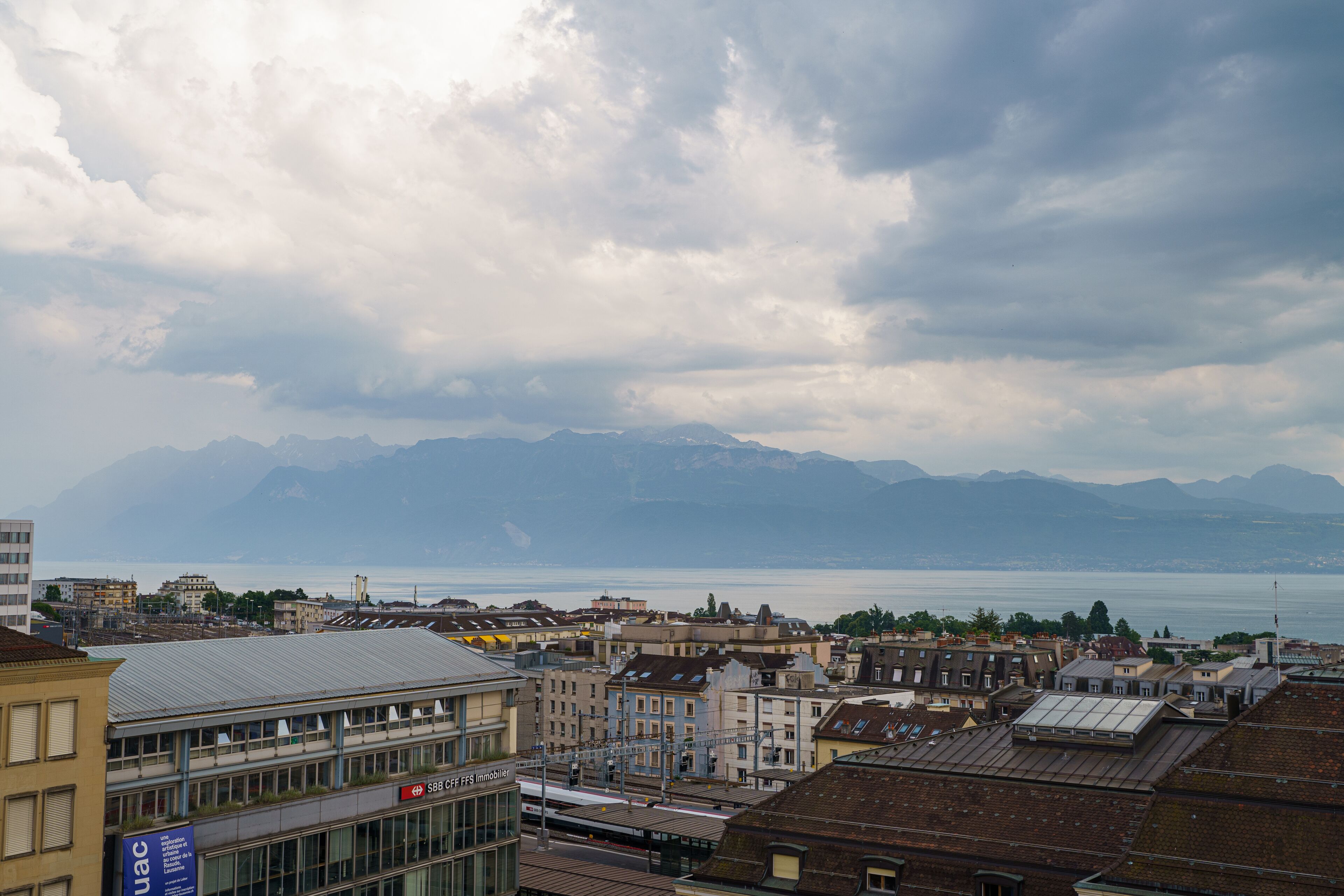 A cityscape with a view of mountains and a body of water in the distance.
