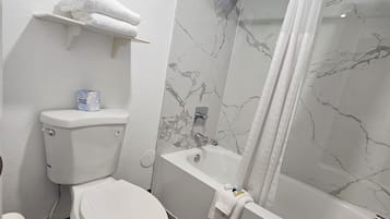 A bathroom with a toilet, a bathtub, and a shower curtain.