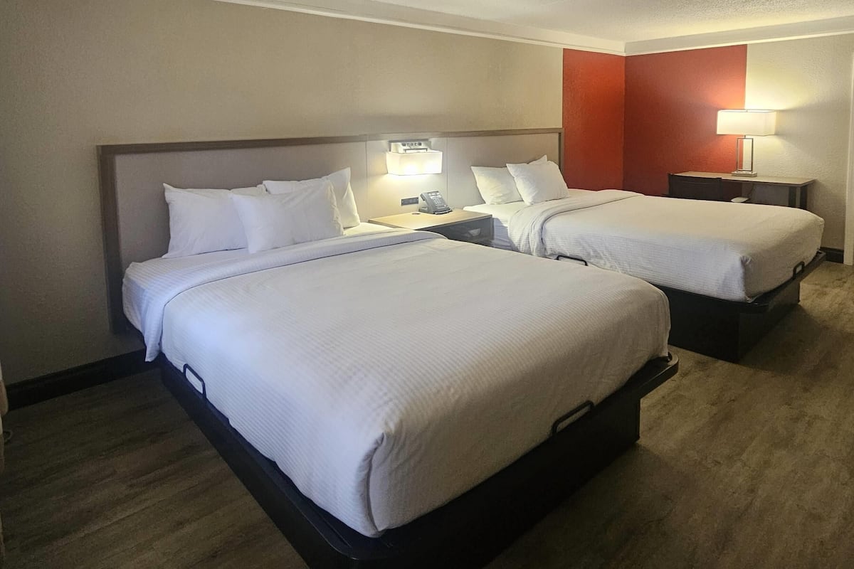 Een hotelkamer met twee bedden, een nachtkastje met een lamp en een kleine tafel.