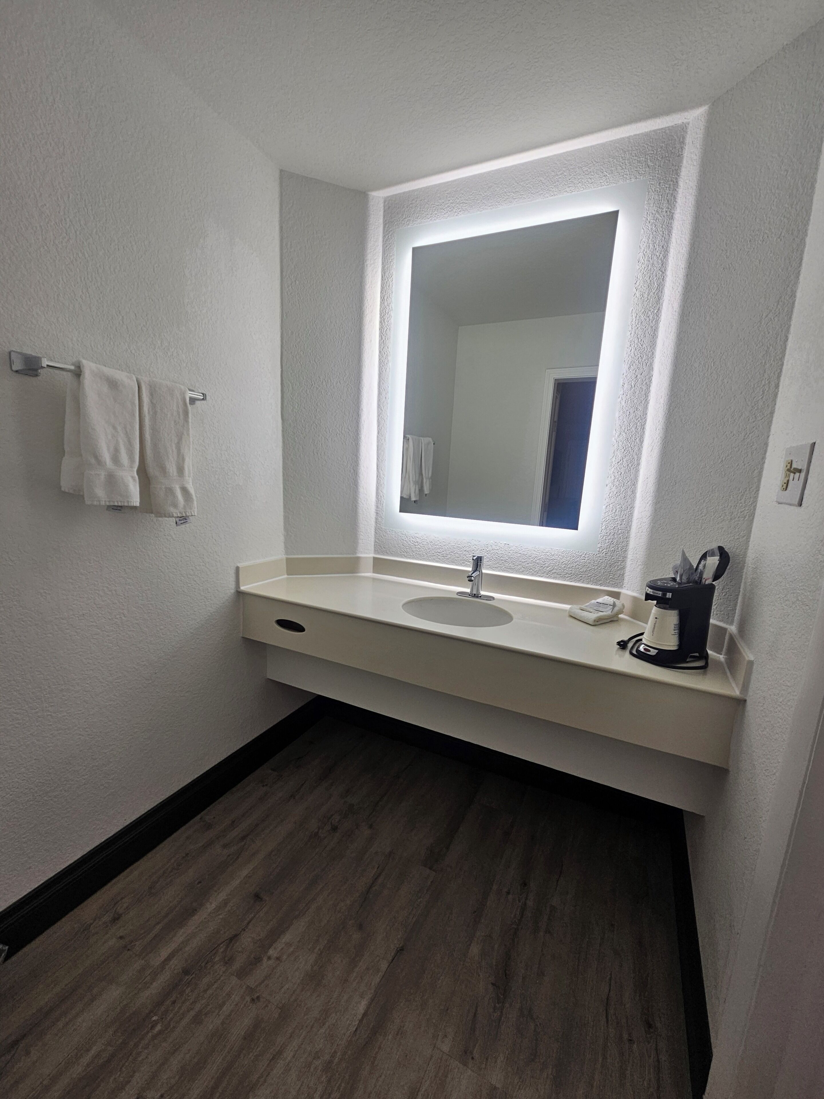 Een badkamer met een wit wastafel, een spiegel en een handdoekhouder.