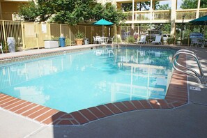 Una piscina al aire libre de temporada, sombrillas, tumbonas