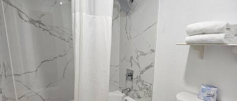 A bathroom with a bathtub, toilet, and a shower area.