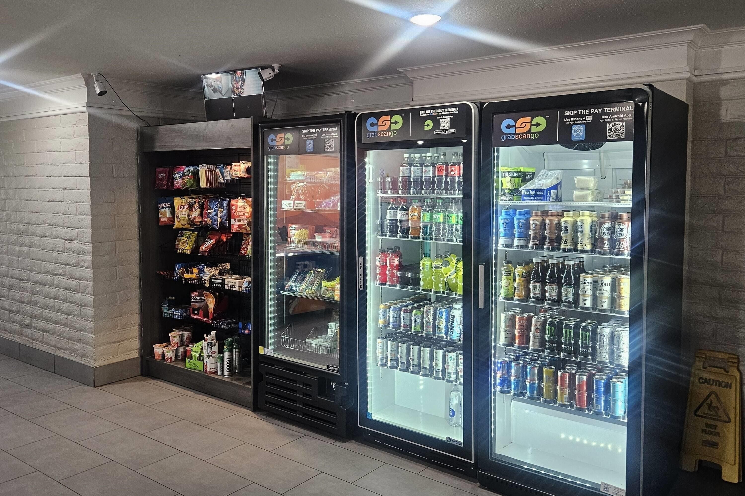 Trois distributeurs automatiques de boissons proposant une variété de boissons et d’en-cas.