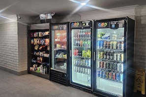 Trois distributeurs automatiques de boissons proposant une variété de boissons et d’en-cas.