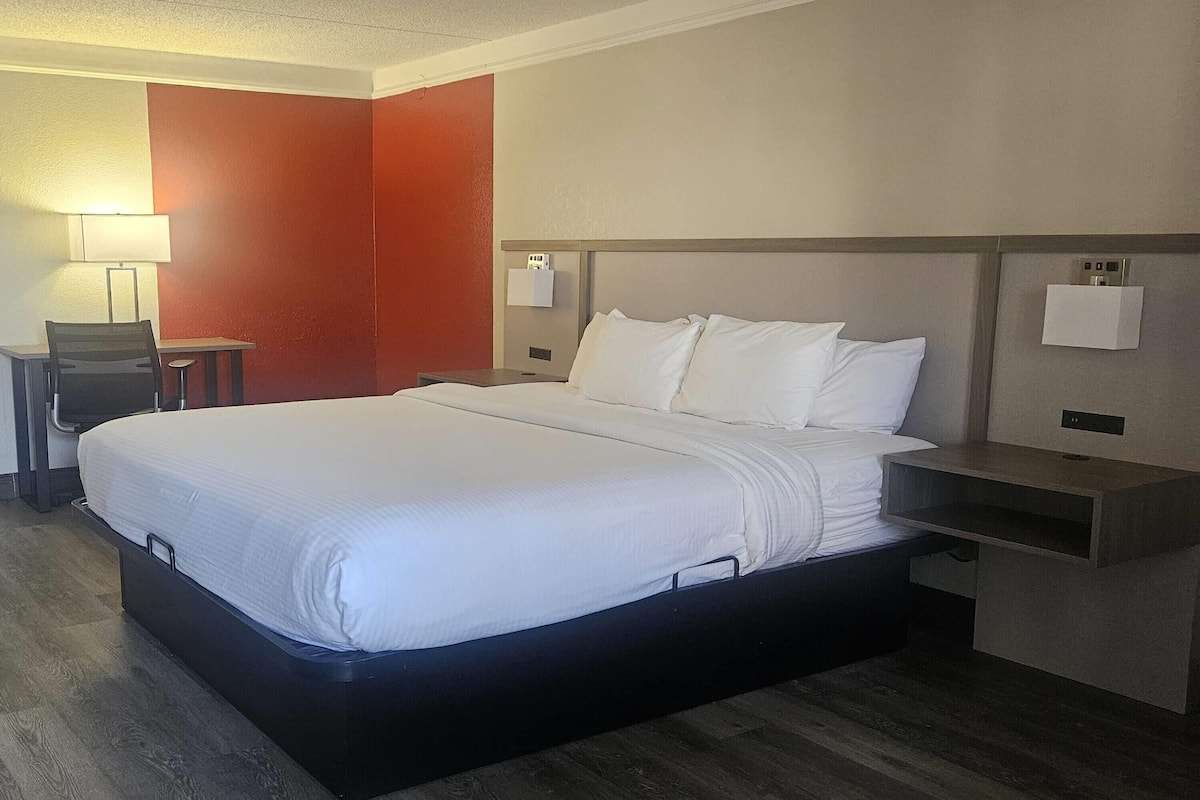 Een hotelkamer met een bed, nachtkastjes, een bureau en een lamp.
