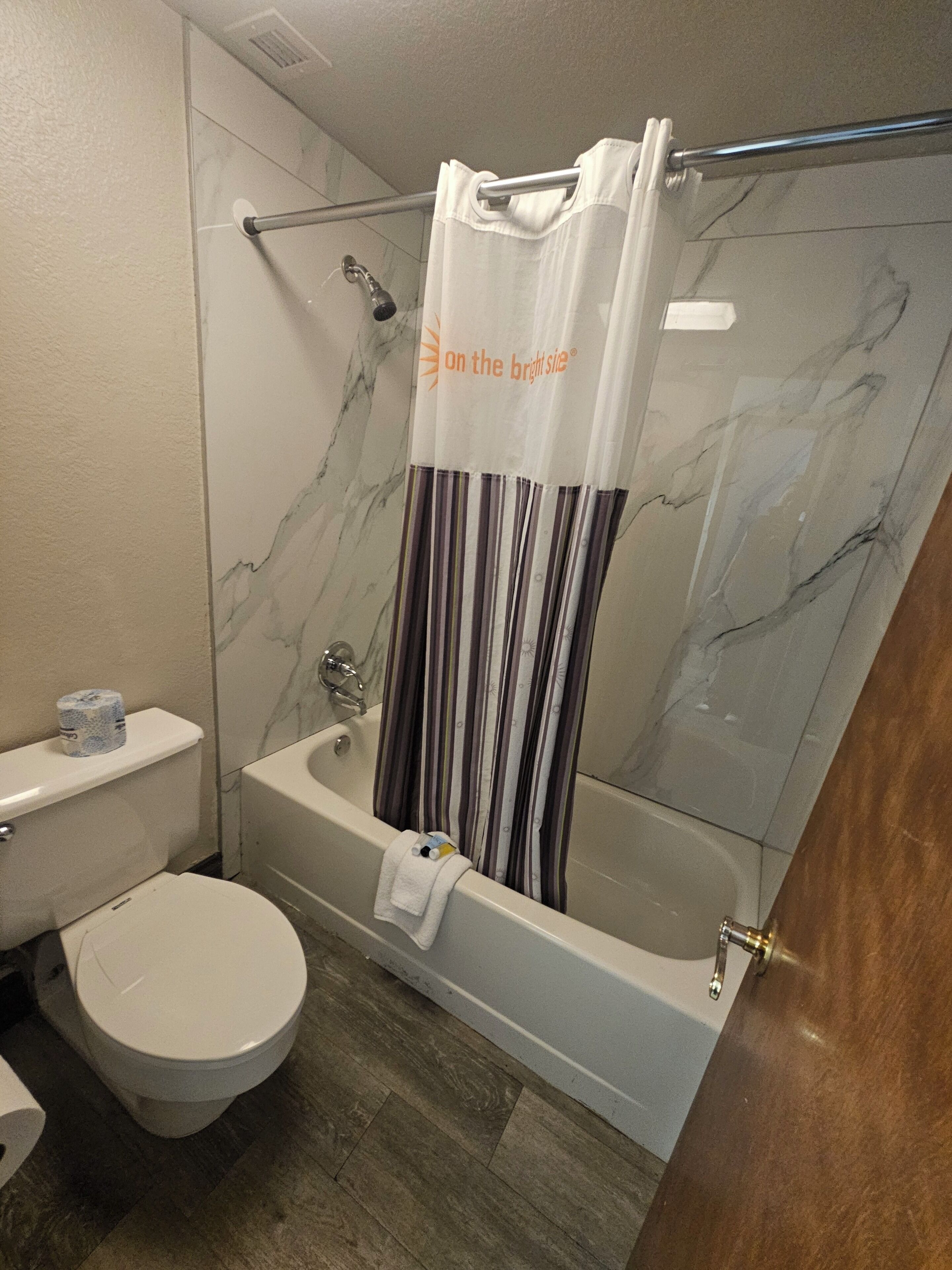 A bathroom with a toilet, a bathtub, and a shower curtain.