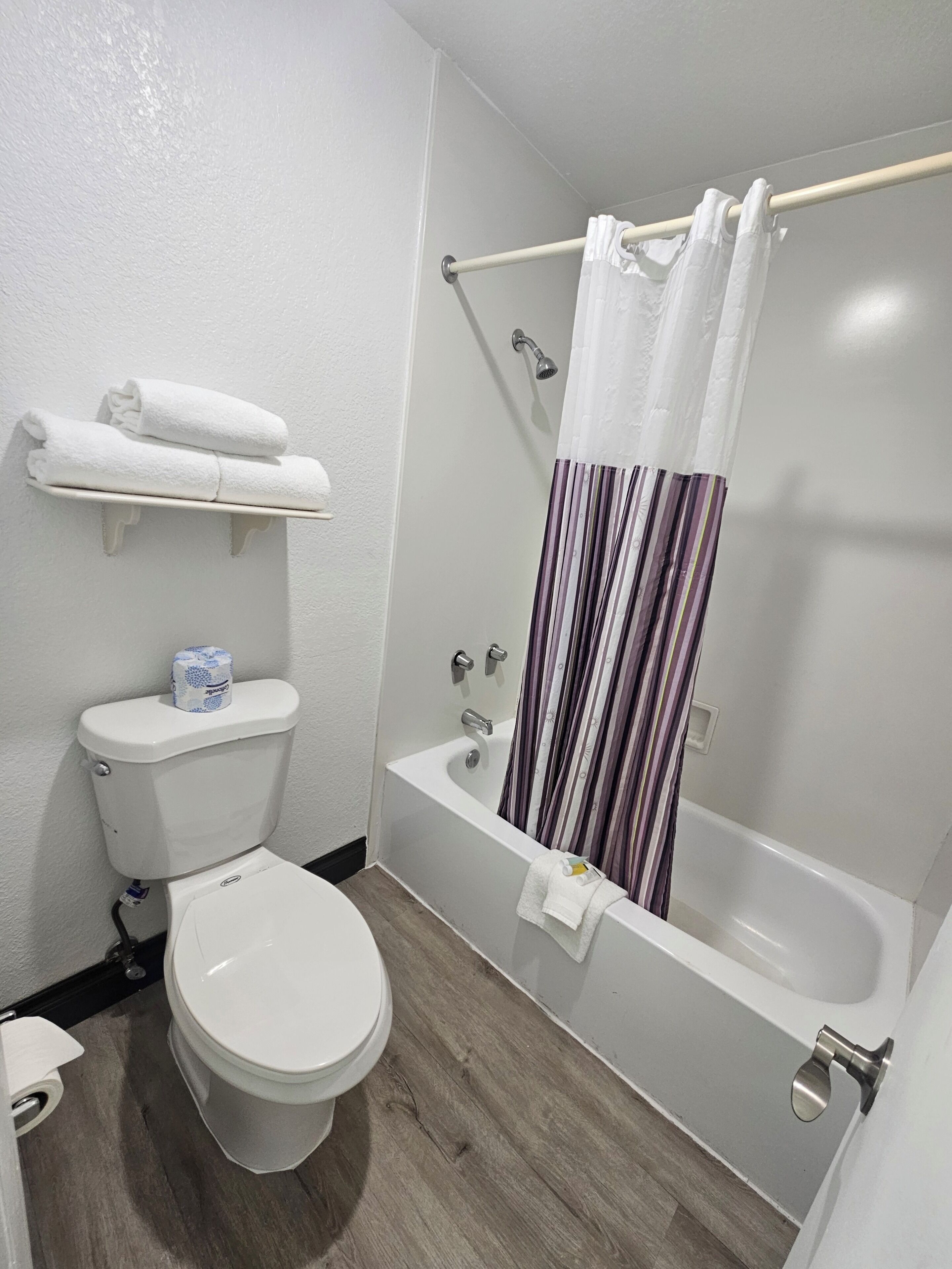 Une salle de bain équipée de toilettes, d’une baignoire et d’un rideau de douche.