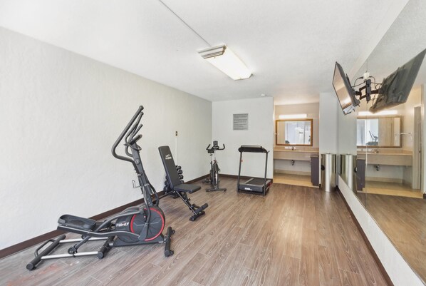 A gym with cardio machines, a bench, and a treadmill.