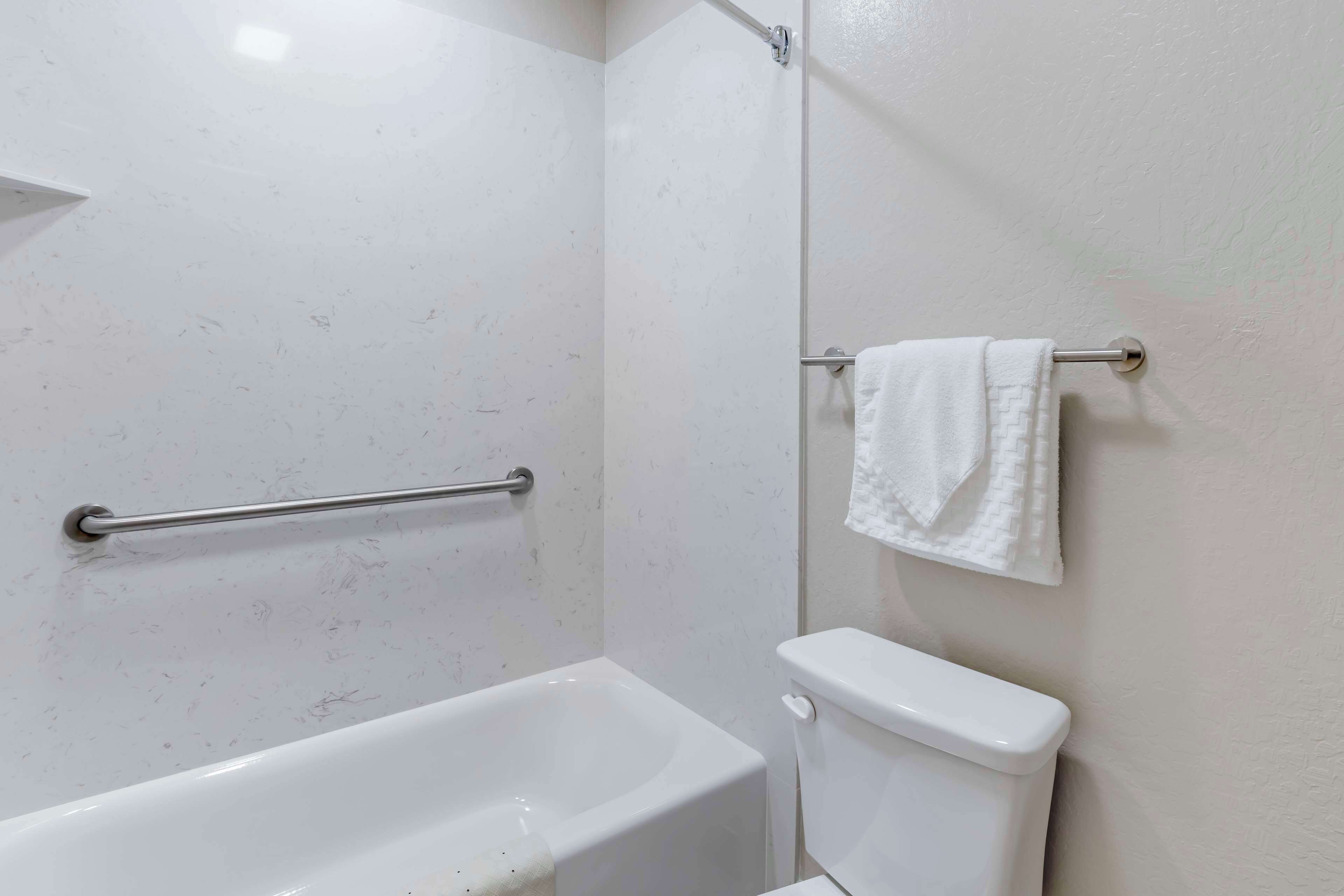A bathroom with a bathtub, toilet, and a towel rack.