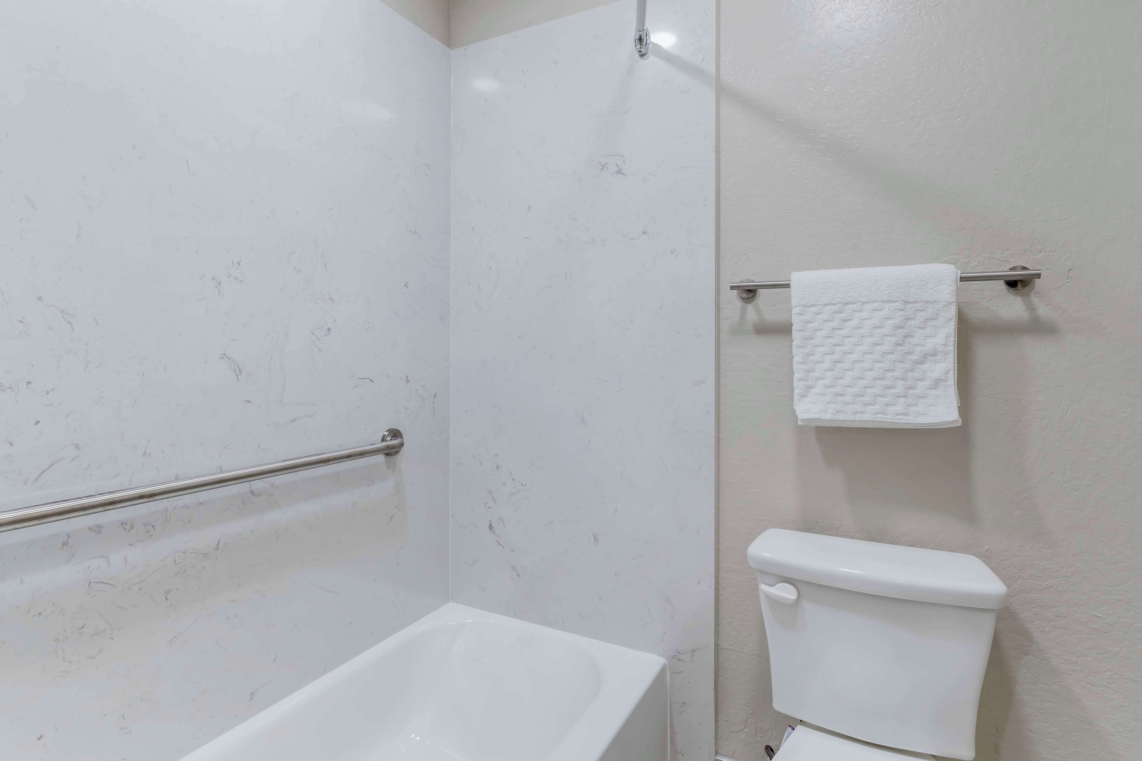 A bathroom with a bathtub, toilet, and towel rack.