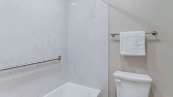 A bathroom with a bathtub, toilet, and towel rack.