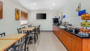 Une cuisine d’hôtel avec un espace buffet, des tables et des chaises pour les repas.