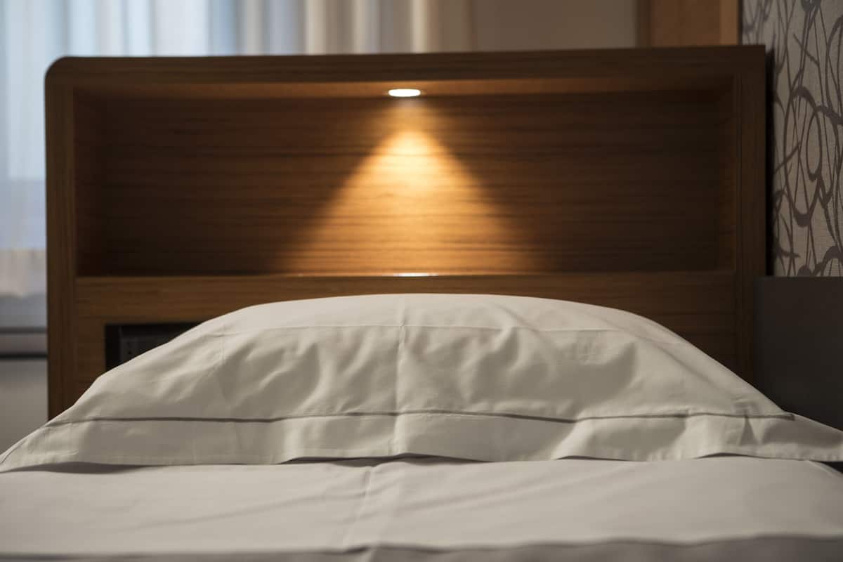Un lit avec une tête de lit en bois et une lampe de chevet.