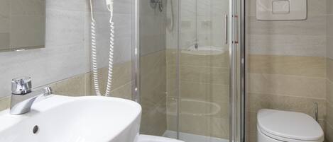 A modern bathroom with a glass-enclosed shower, a white sink, and a toilet.