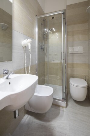 Une salle de bain moderne avec une douche à parois de verre, un lavabo blanc et des toilettes.