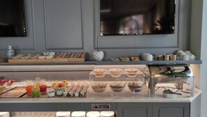 A breakfast buffet with various food items and beverages, a coffee machine, and a display of plates and cups. - Hotel Astra Ferrara (Ferrara)