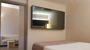 A hotel room with a bed, a sofa, a small table, and a large mirror on the wall. - Hotel Astra Ferrara (Ferrara)
