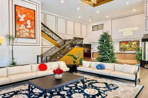 A spacious lobby with a white sofa, a coffee table with red flowers, a staircase, and a Christmas tree.