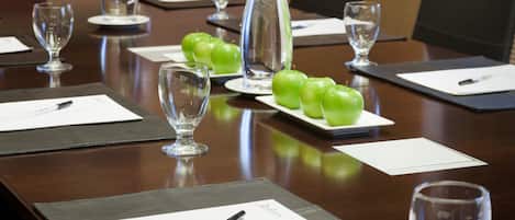 A conference table with green apples, water glasses, and documents.