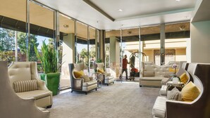 Eine großzügige Lobby mit Ledersofas, einem grünen Pflanzenbeet und großen Fenstern mit Blick ins Freie.