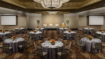 A conference room with multiple round tables, each set with chairs and floral centerpieces.