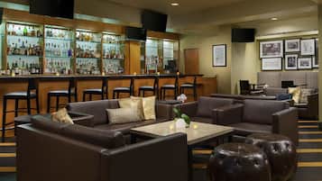 A bar area with leather sofas, a coffee table, and a bar stocked with bottles.