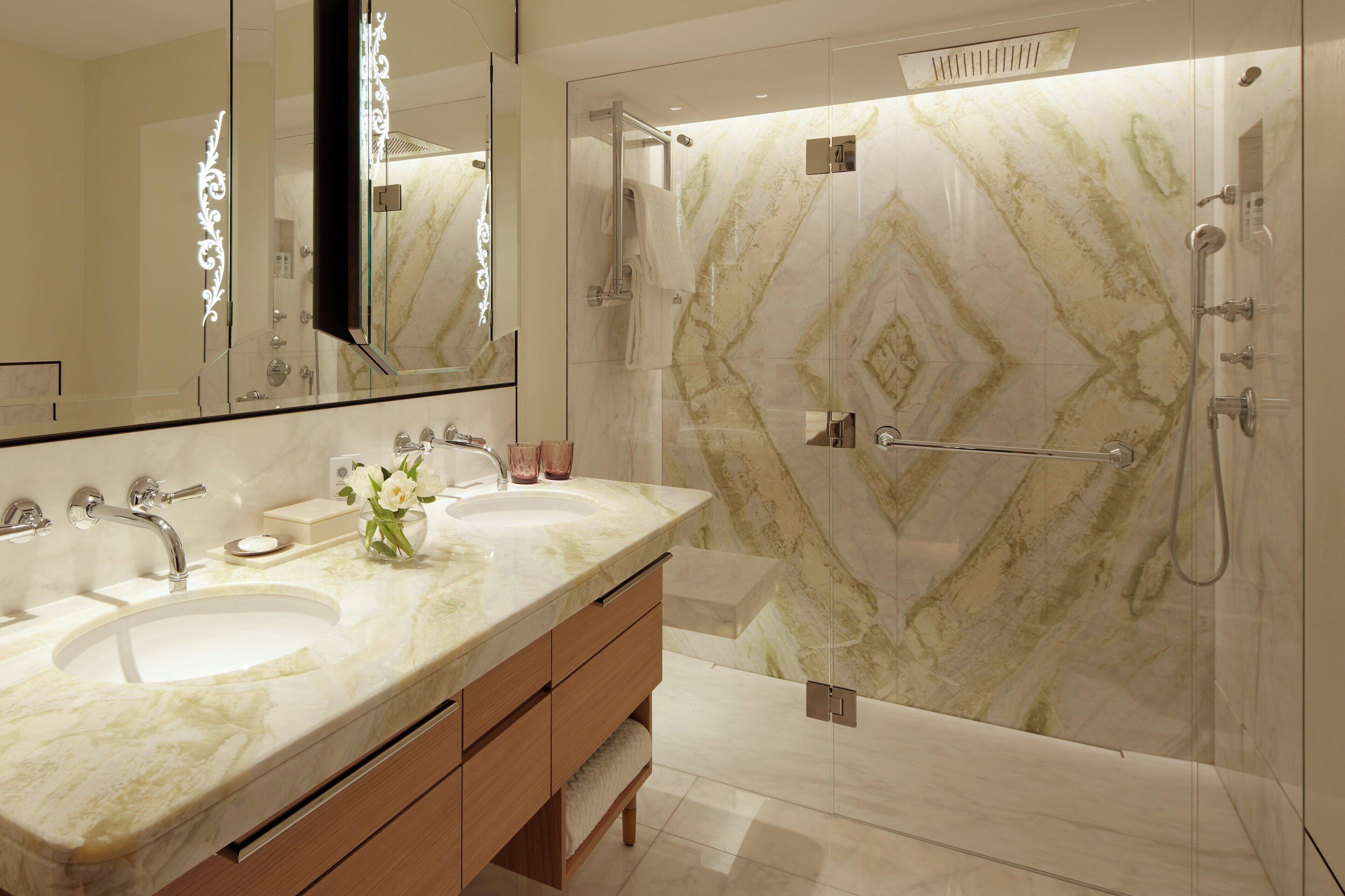 A modern bathroom with two sinks, a large mirror, and a shower area.