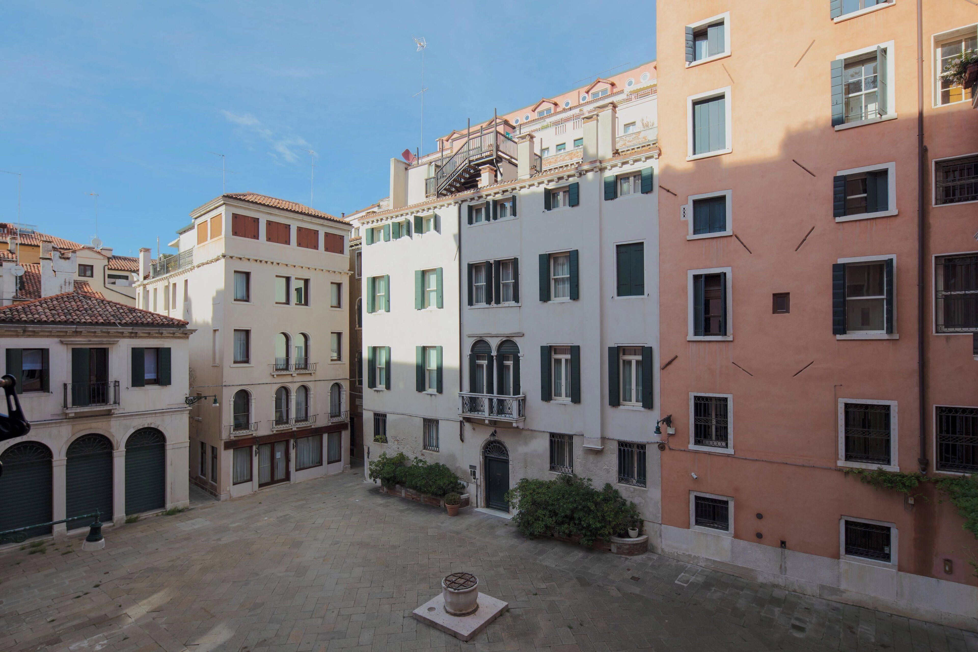 Un patio con edificios que tienen balcones y ventanas, rodeado de plantas en macetas.