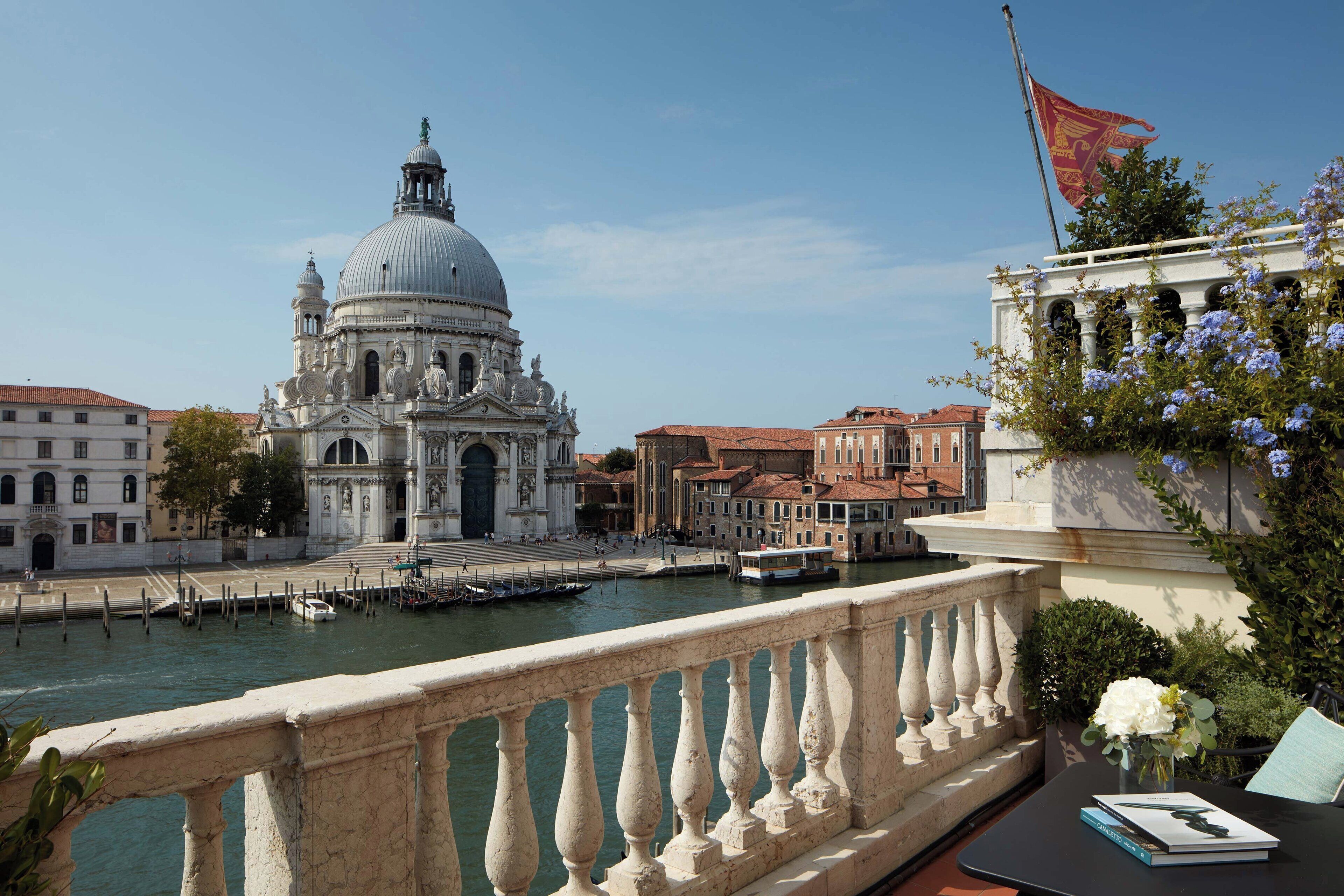 A view of a historic building with a dome, a bridge, and a flag.