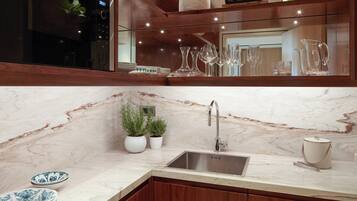 A kitchen with a marble countertop, a stainless steel sink, and wooden cabinets.