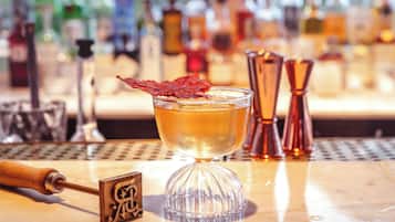A bar setting with a cocktail glass, a cocktail shaker, and a bottle of liquor in the background.
