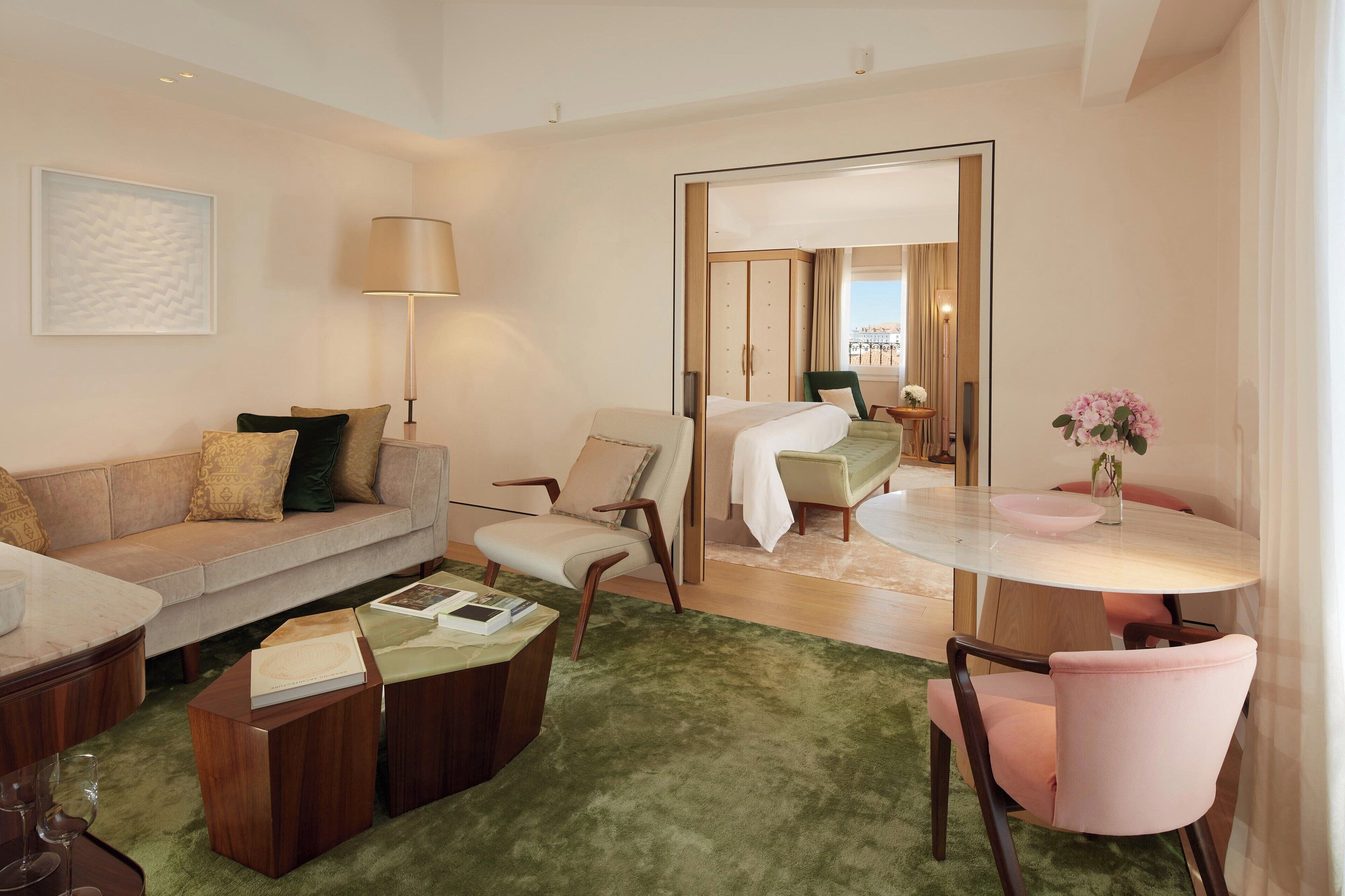 Una habitación de hotel moderna con zona de estar, una mesa de comedor y una cama.
