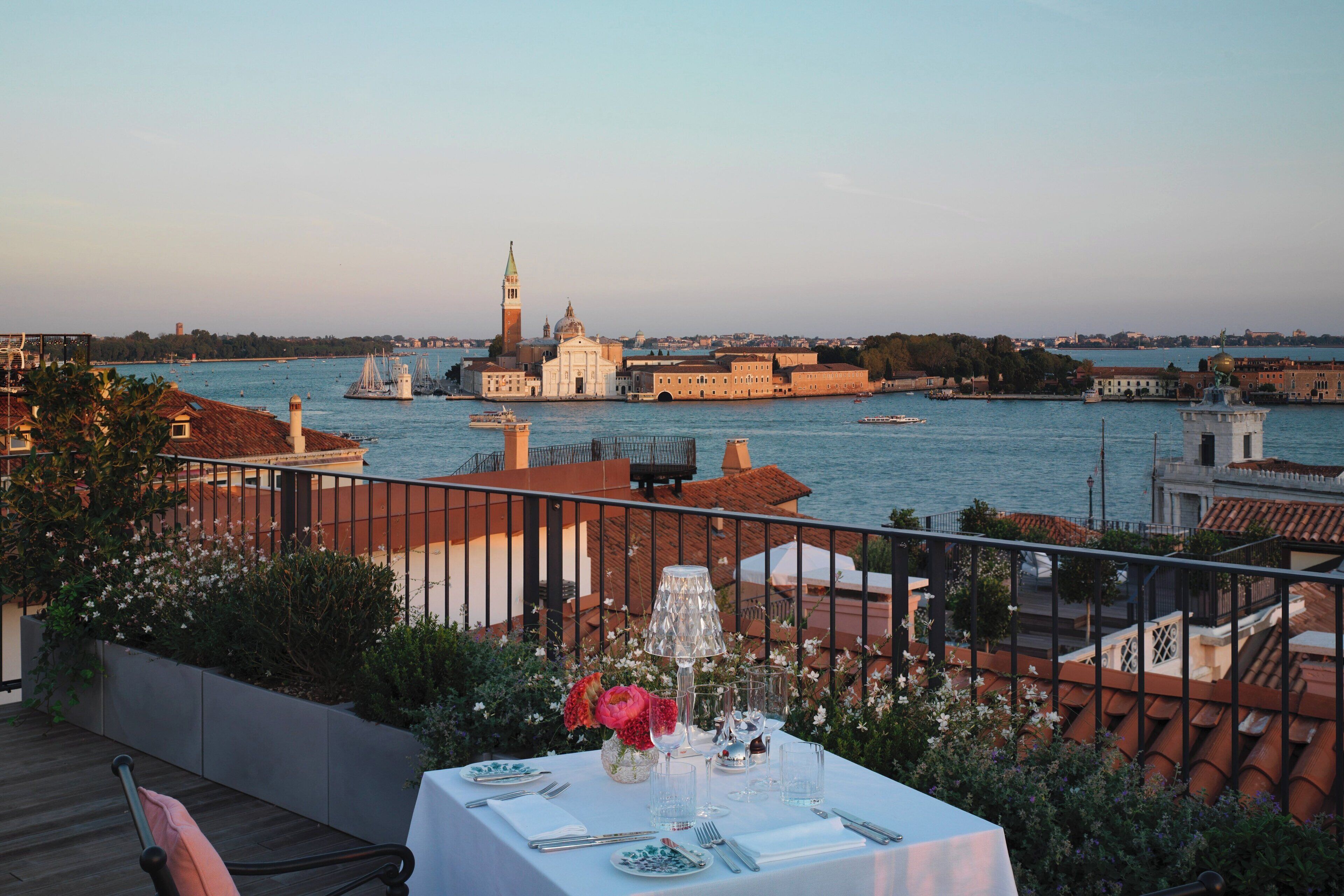 Une table dressée pour le dîner, offrant une vue sur un paysage urbain historique et sur l’eau.