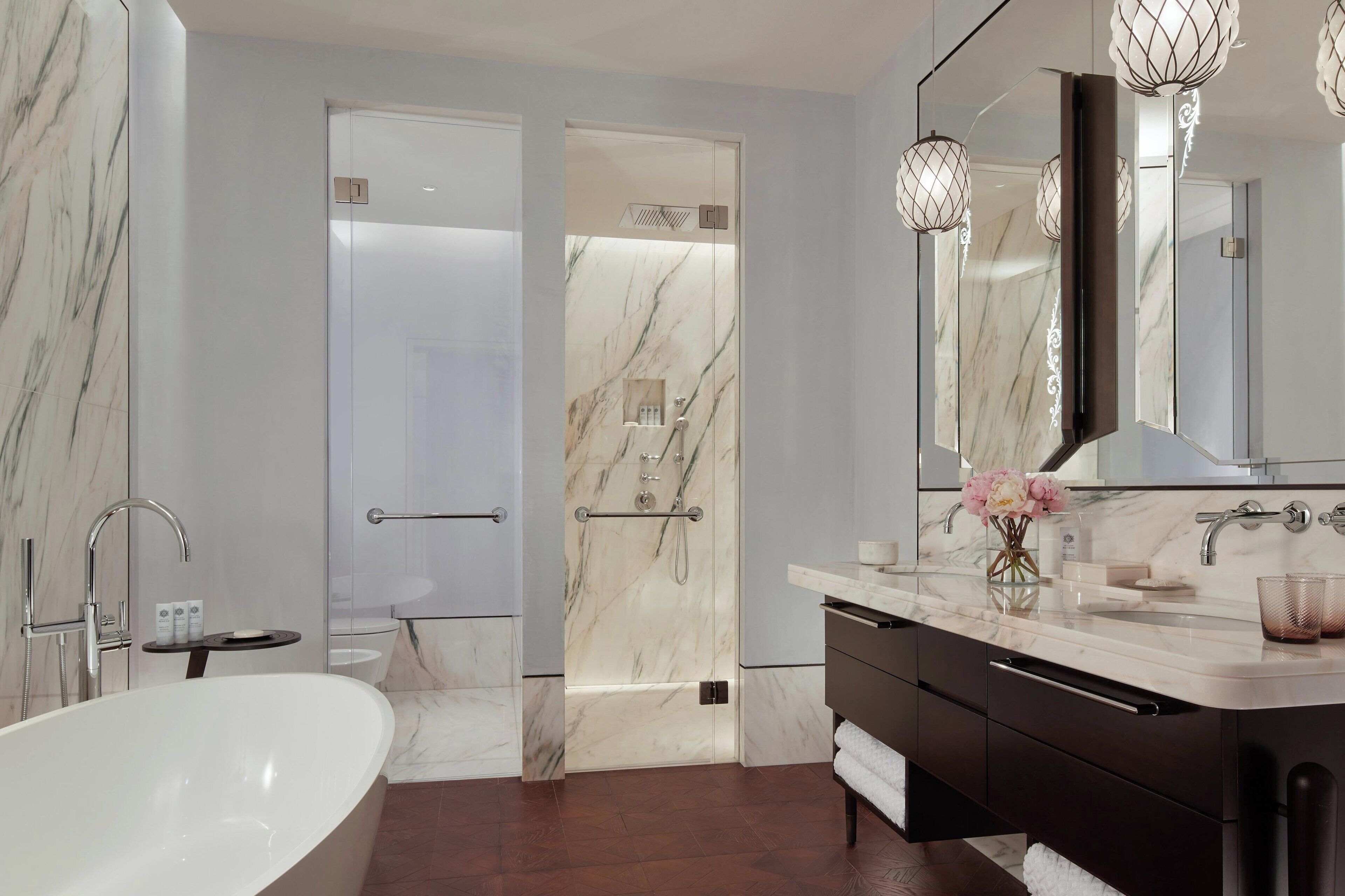 Une salle de bain moderne avec une baignoire sur pieds, un grand miroir et un meuble-lavabo doté d’un plan en marbre.