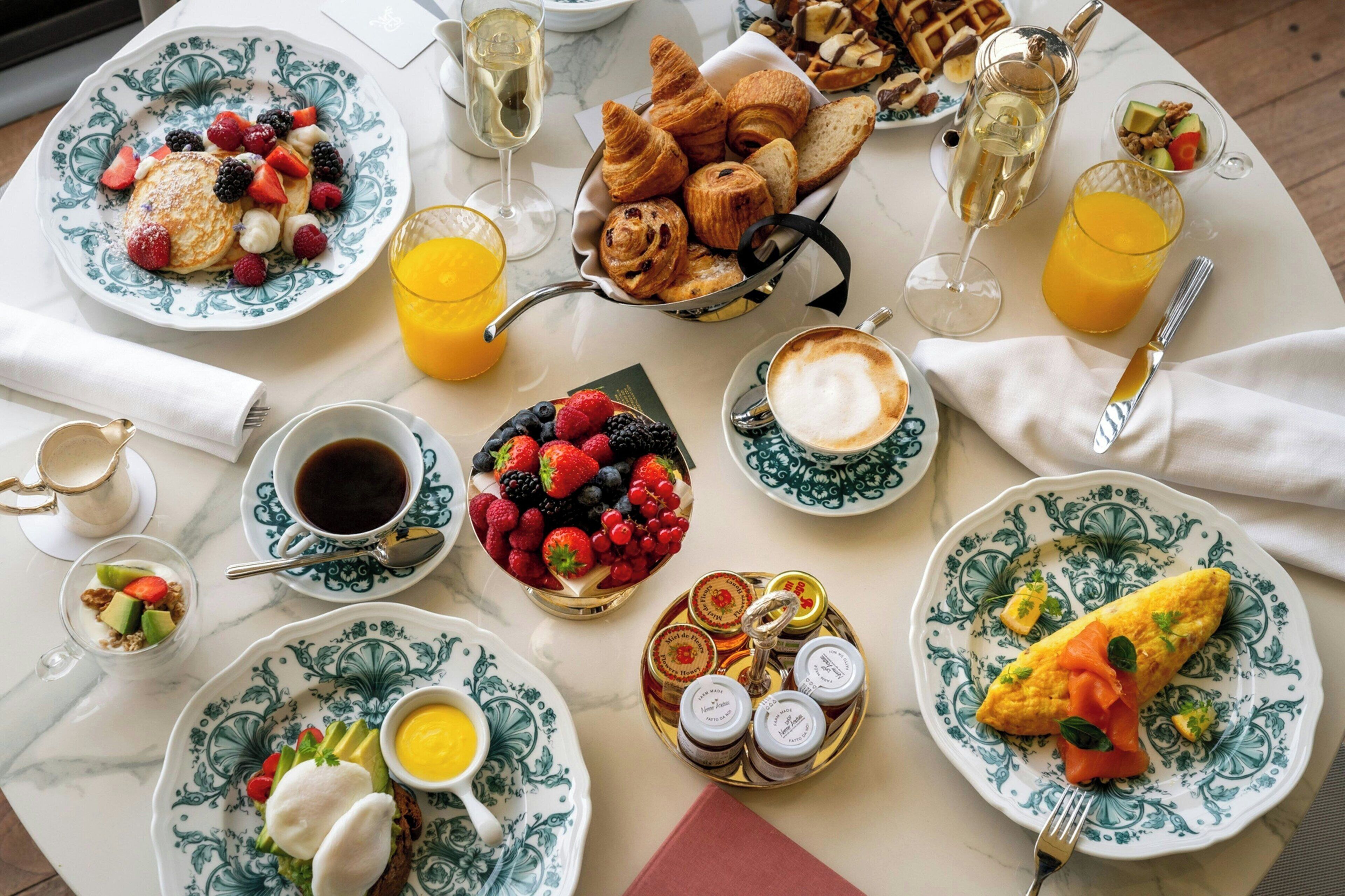 Een ontbijttafel met croissants, gebak, fruit, koffie en diverse toevoegingen.