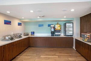 Un área de cocina moderna con servicio de autoservicio, que incluye una estación de yogur y huevos, una máquina de café y un microondas.