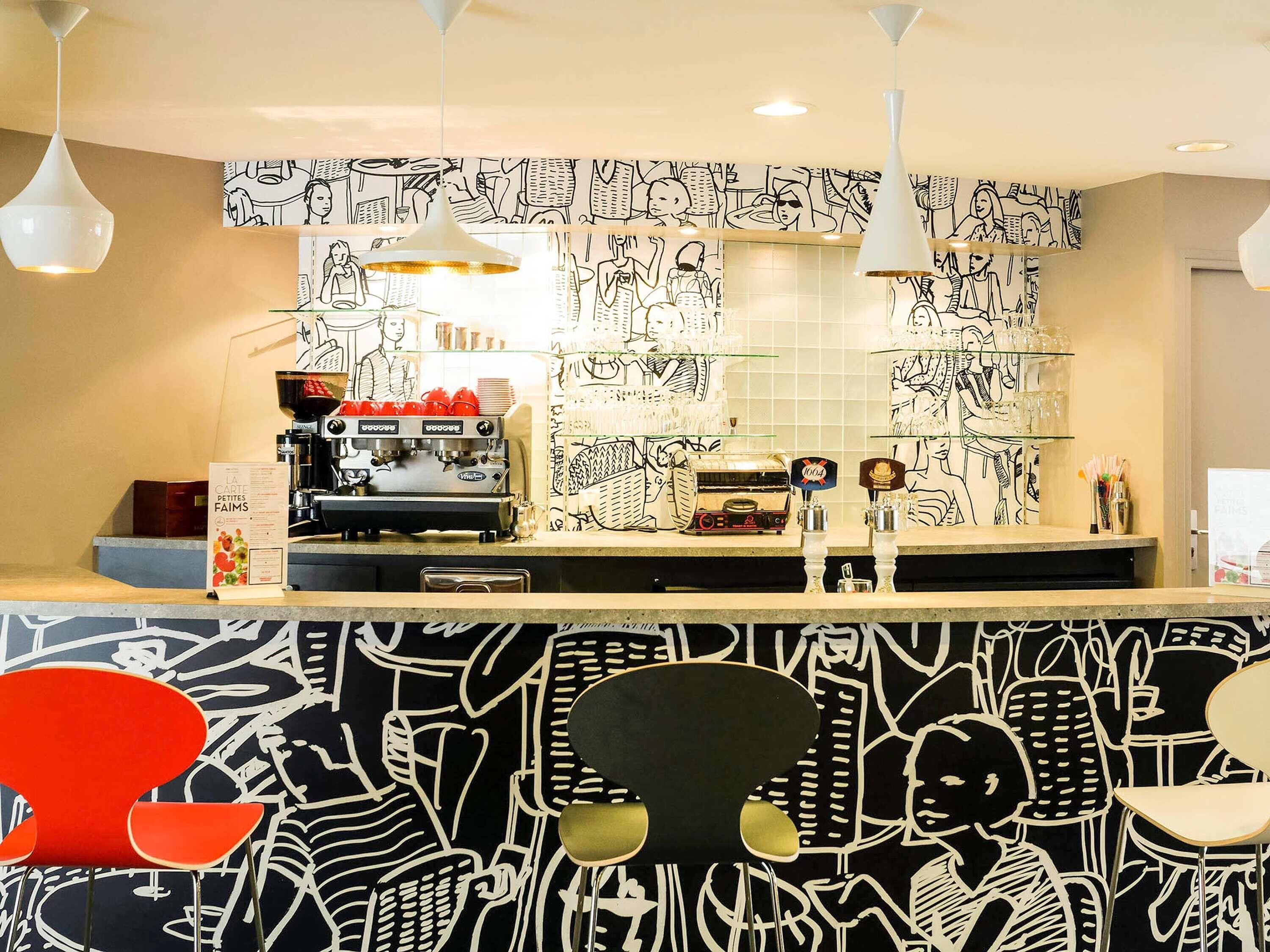 Un espace bar équipé d’une machine à café, de verres et d’un présentoir à menus.