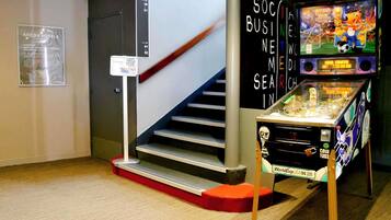 A staircase with a sign indicating the direction to the 1st floor, a coin toss game machine, and a poster for ACCOR Hotels.