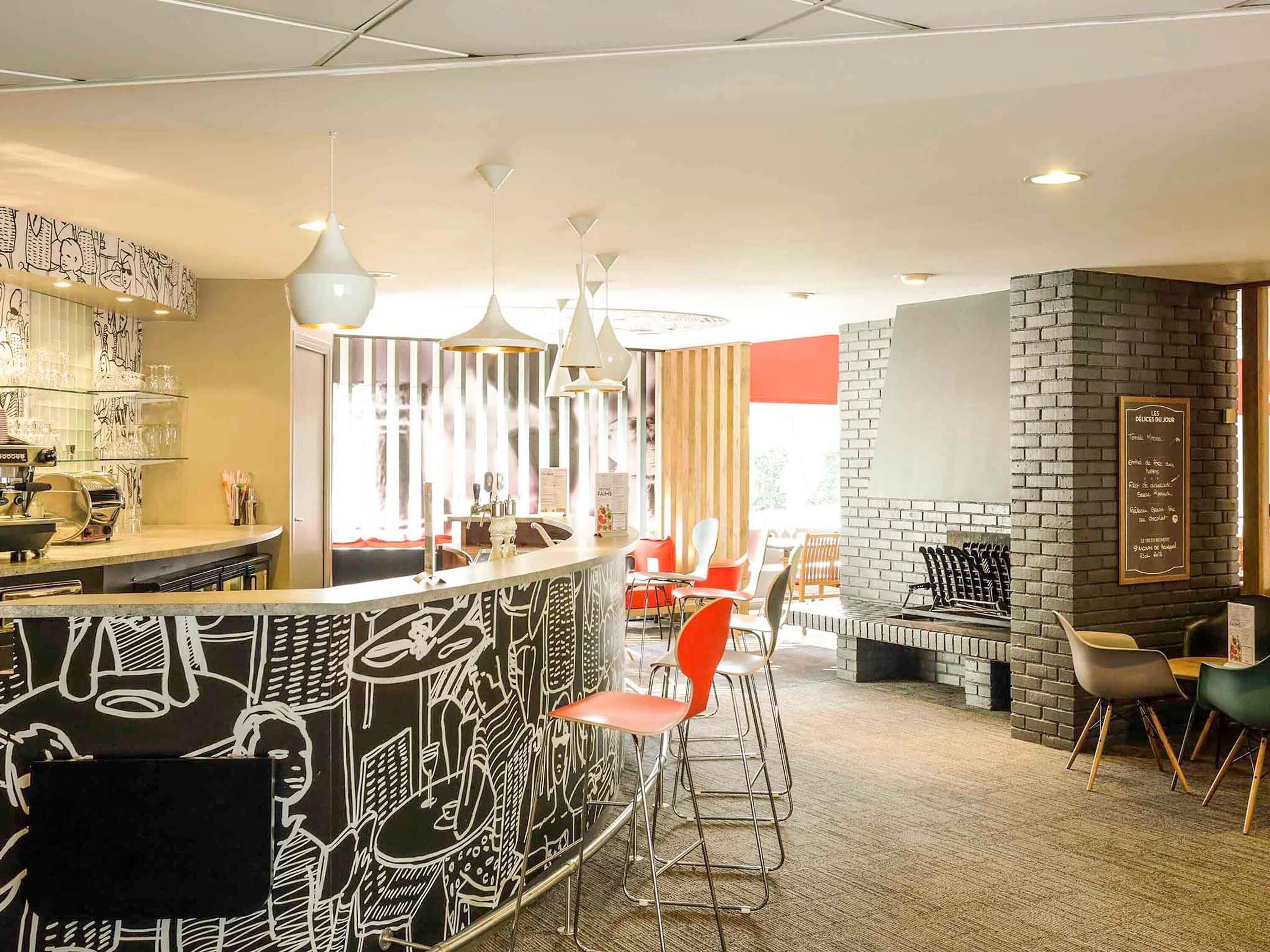 Un área de bar moderna con mostrador, taburetes e iluminación colgante.