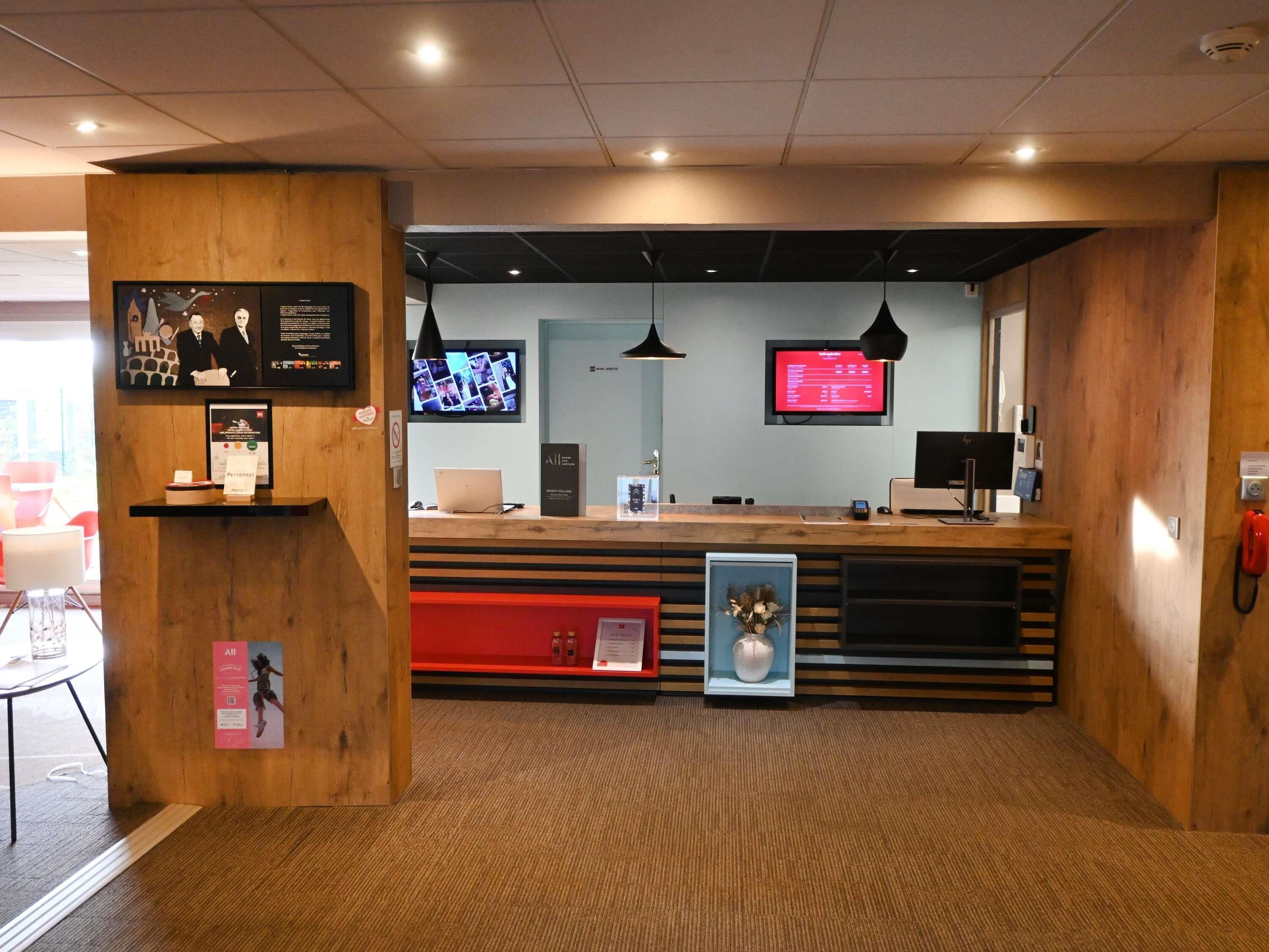 A reception desk with a computer, a television, and a telephone.