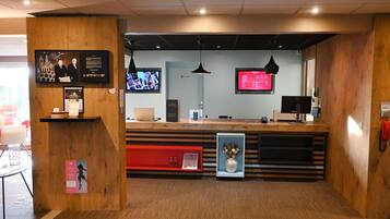 A reception desk with a computer, a television, and a telephone.