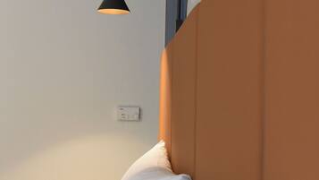 Ein Schlafzimmer mit Bett, Nachttisch, Wandlampe und Thermostat.